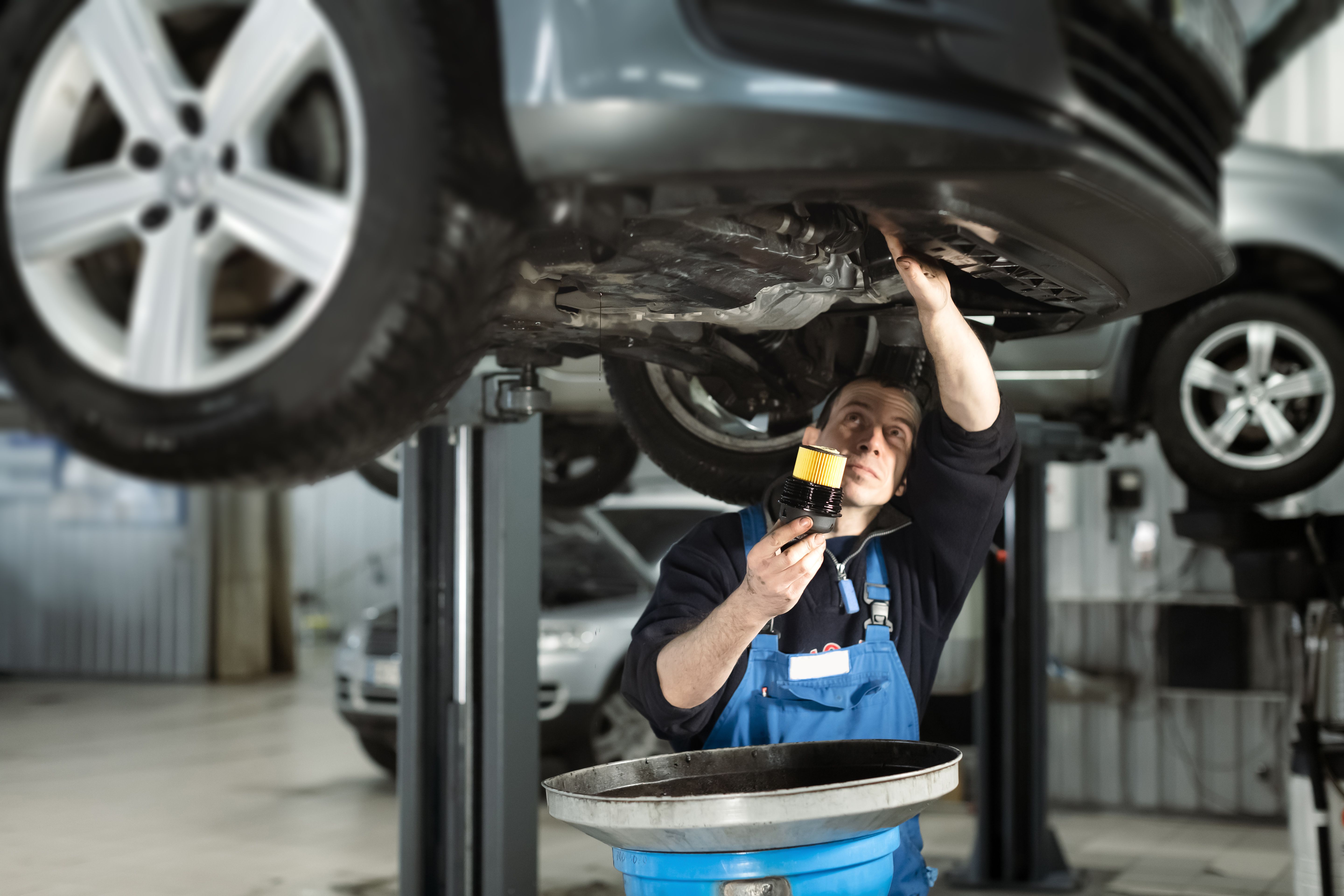 Automotive repair person replacing an oil filter