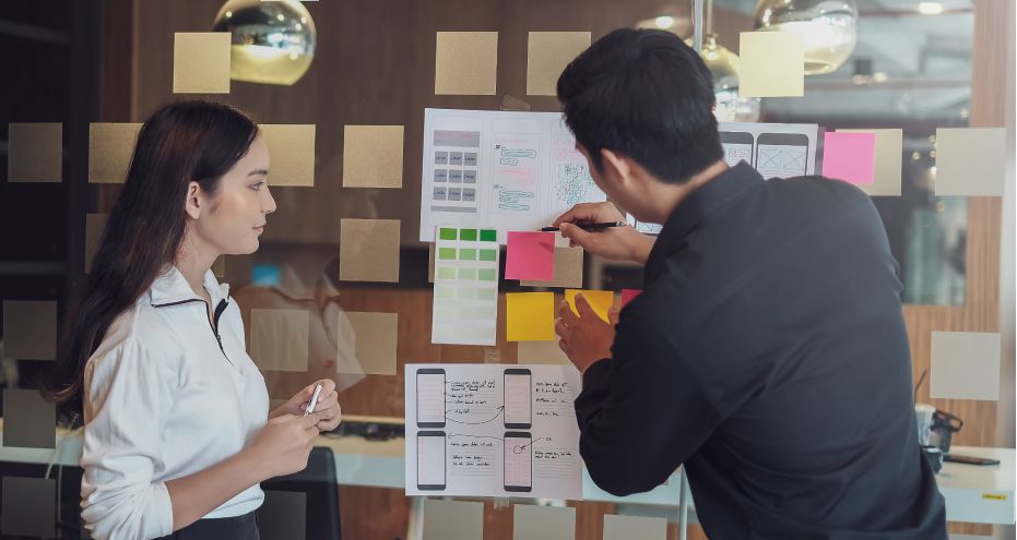 Two designers creating a storyboard on a wall