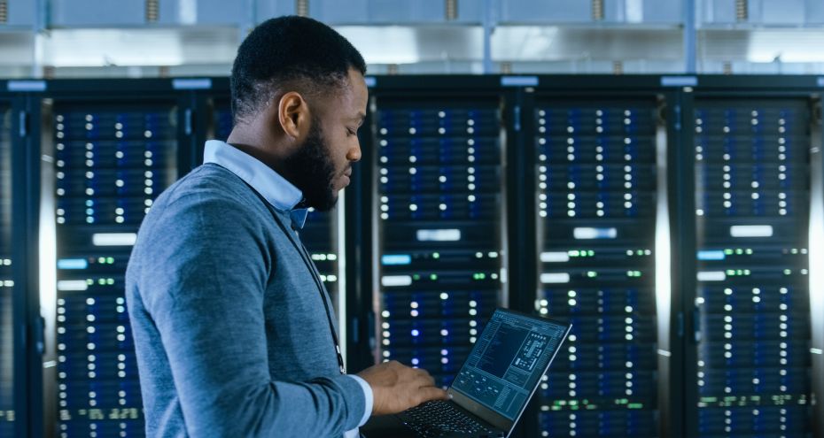 IT Professional in a server room looking at a laptop